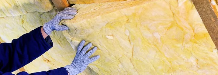 Person beim Dämmen eines Dachstuhls